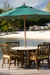 table and chairs with sun awning by sandy beach