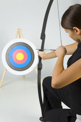 Young lady archer holding bow and taking aim at targer