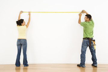 Couple measuring wall.