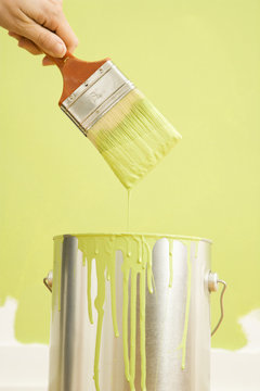 Caucasian Female Hand Holding Paintbrush Over Paint Can.