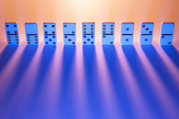 Row of dominos with light casting long shadows. 