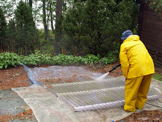 Man cleans plastic roof with high presure water, view