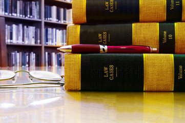 Law books stacked in a library, with pen and glasses