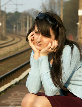 Young girl waiting for the train on the empty railway platform