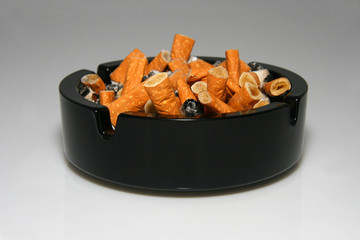 Black glass round ashtray full of stubs.