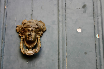 Old door knocker on old painted wall.