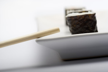 Composition of maki sushi, white late and a stick. 