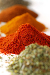 Heaps of various ground spices on white background