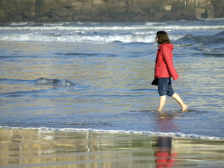 Mujer paseando por la orilla de la playa