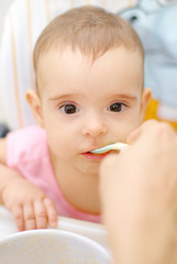 Adult hands giving food in spoon for a Baby