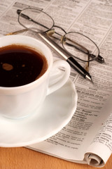 Coffee cup with glasses and newspaper