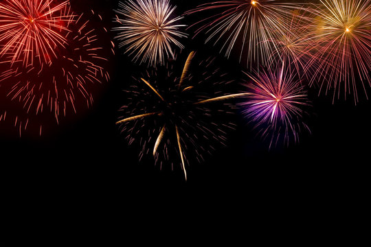 Multiple brightly coloured fireworks exploding