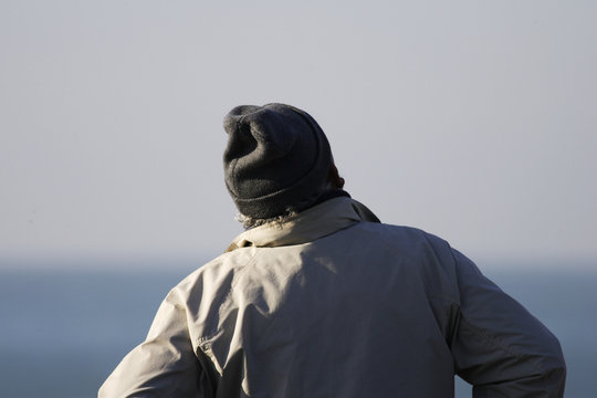 homme avec un bonnet qui regarde la mer