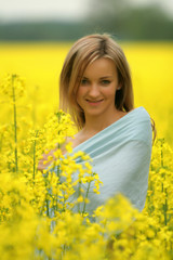 Naklejka na ściany i meble Girl stands in yellow flower field - very cute portrait
