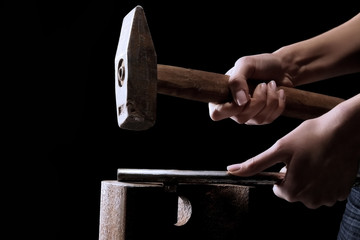 woman hands holding hammer which is hitting a pipe