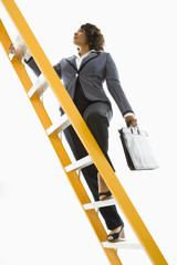 Businesswoman holding briefcase climbing ladder. - 5440101