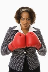 Businesswoman wearing boxing gloves looking serious.