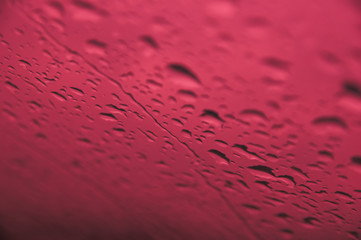 Rain drops on window with red background