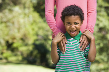 Boy in park making funny expression with mother.