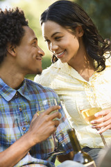 Couple getting close having wine on romantic park picnic.