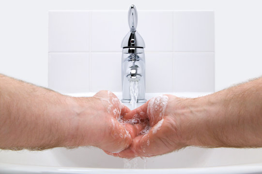 Man washing his hands with soap under running water.