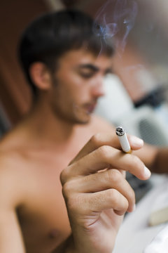 jeune homme fumeur a la maison en été cigarette à la main