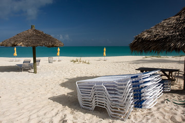 sun beds with thatched sun shade on beach with turquoise sea