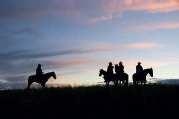 Cowboys silhouetted against a dawn sky. Montana horse ranch