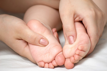 An image of woman's hands and child's foots.