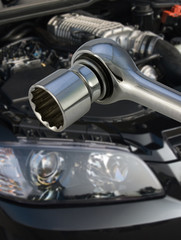 Socket spanner with V8 supercharged car engine in the background