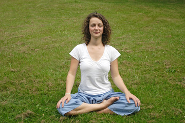 Junge Frau im Yogasitz auf einer Wiese