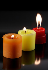 candles on black background, reflecting their lights