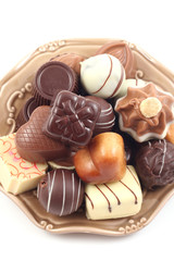 various delicious pralines on plate isolated on white