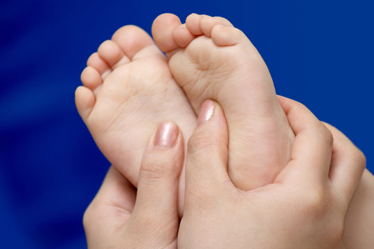 Woman's hands holding a child's foots.