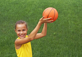 Preteen girl with basketball on grass background