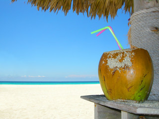 tropical coconut cocktail under beach umbrella on a sandy beach