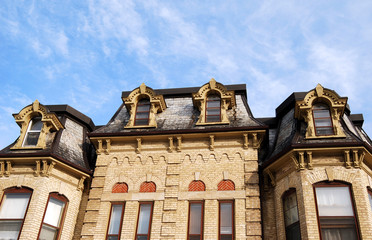 Yellow brick Victorian house with mansard roof and dormers