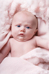 A blue eyed newborn portrait on a pink blanket