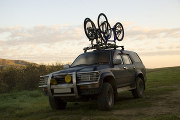 Two sports bicycles over jeep at sunrise in trip