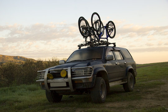 Two sports bicycles over jeep at sunrise in trip