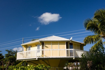 single white cloud over yellow house with balcony