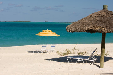 sun loungers under umbrellas on tropical beach