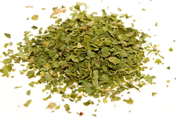 Dried, crushed parsley flakes isolated on white.