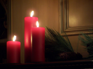 Red Candles on mantle with pine boughs and cone