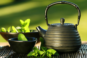 Fototapety  Czarny żelazny azjatycki czajniczek z gałązkami mięty na herbatę