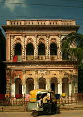 A three wheeler taxi passing by the old building