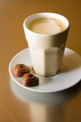 A cup of cappuccino with two coffee chocolates