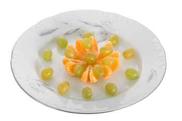 Peeled tangerines and grapes on plate isolated on white