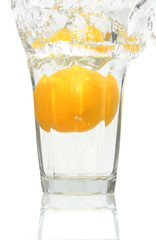 lemon falling into a glass of ice cold water