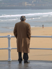 Hombre con abrigo mirando al mar